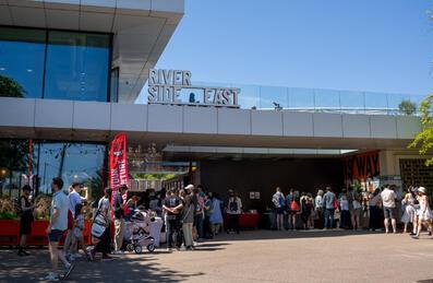 A crowd of people outside Riverside East on a sunny day