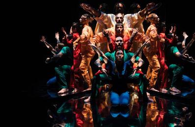 A group of people on stage with interlocked arms