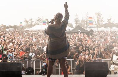 A person on stage at UK Black Pride with the crowd in the background
