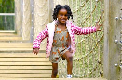 A little girl runs across the rope bridge at Tumbling Bay Playground