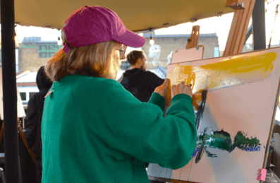 A woman in a pink cap painting a white canvas
