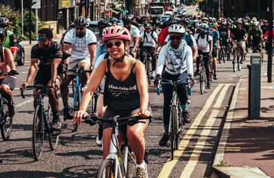 A group of Black cyclists ride along a road