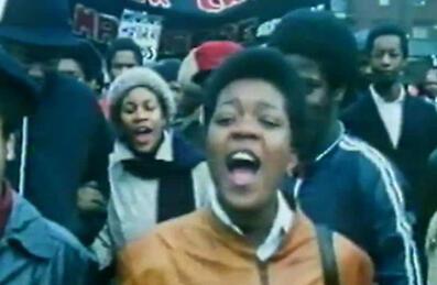 A group of people on a march shout and smile