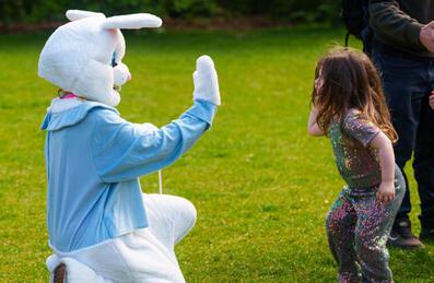 a large easter bunny high fives a child