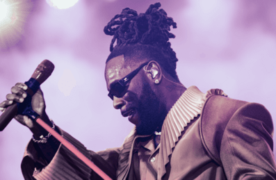 Burna Boy holds his up his mic on stage