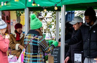 A Christmas market at Barge East with two people buying from a stall