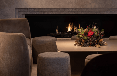 A room with a fire burning and a christmas wreath on a table