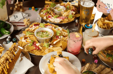 A circle of hands reach out for food on a table.