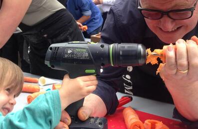 A person holds a carrot on the end of a drill
