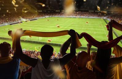 A crowd of fans hold up scarves at a football match