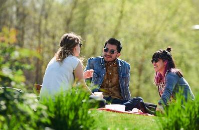 Three people sit on some grass for a picnic