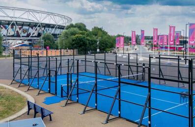 A blue padel court with a stadium in the background