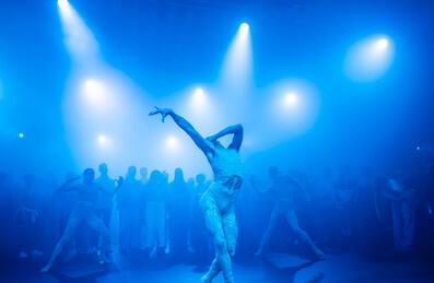 A group of dancers performing in blue light