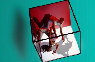 A conceptual image of two men dancing within a rotating cube.