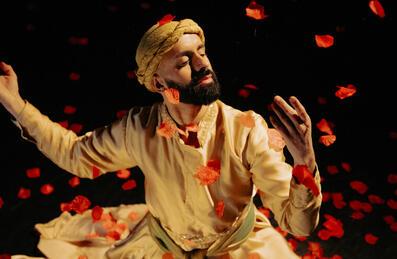 A man in a turban dancing amongst falling petals