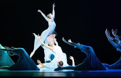 A dance performance in blue and green light