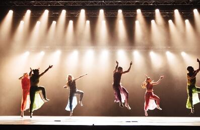 A group of dancers performing on stage with lots of overhead lights