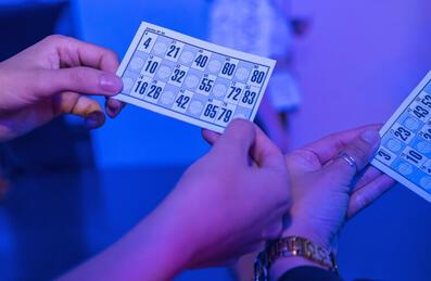 Two people hold up bingo cards