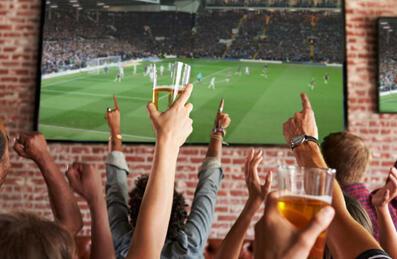 A group of people cheering at a sports screen