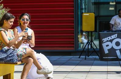 Two people enjoy listing to a DJ at Stratford Cross