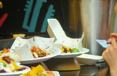 A person stands at the hatch of a street food van with food on the counter