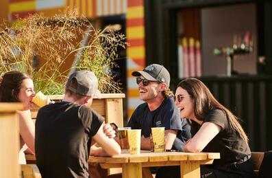 People laughing and drinking at Riverside East on Queen Elizabeth Olympic Park
