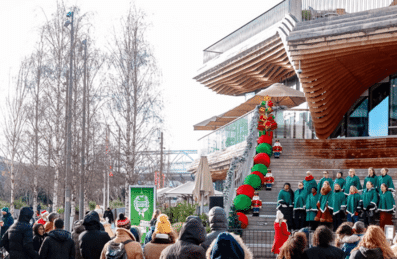 A choir performing for a crowd with the ArcelorMittal Orbit in the background