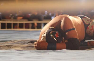 A wrestler lies prone on the canvas of the ring