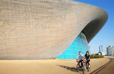 Cyclists in front of London Aquatics Centre