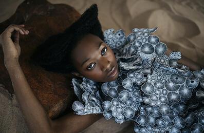 A person lies back in a designed outfit 