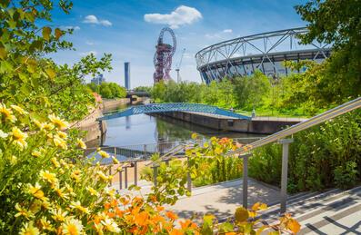 View of the Park with a bridge over the river and the ArcelorMittal Orbit and London Stadium in the background