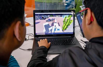 Two boys designing a computer game on a laptop