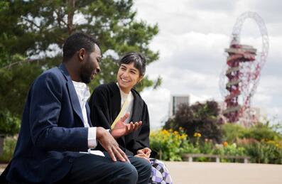 Two business people talking with the ArcelorMittal Orbit in the background