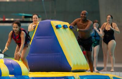 a young girl crawls along an inflatable of Aqua Splash