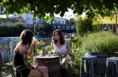 Two young women having a drink outside in Barge East gardens