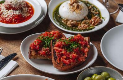 An Italian food platter with bruschetta, olives and burrata