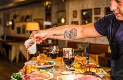 A chef pouring gravy on a roast at The Lock Inn