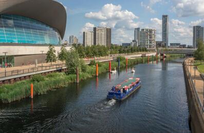 a boat tour travels downriver by London Aquatics Centre