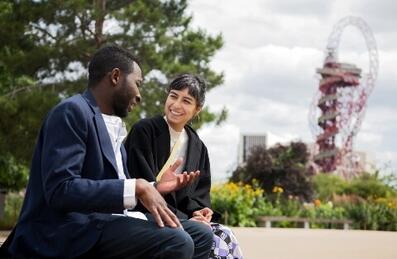 A man and women chatting with ArcelorMittal Orbit in the background