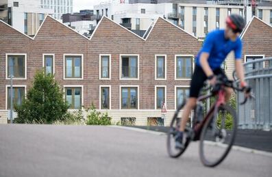 A cyclist goes past housing on Queen Elizabeth Olympic Park