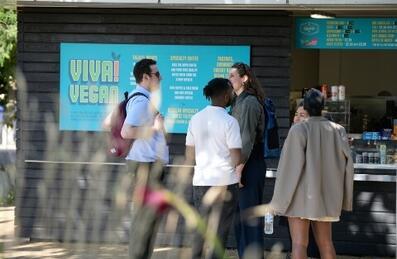 A group of people chatting outside a food kiosk