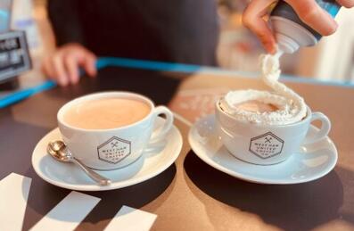 a barista serving hot chocolate with whipped cream